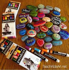 there are many different colored rocks and markers on the table with some crayons next to them