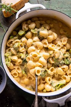 a pot filled with pasta and broccoli on top of a table