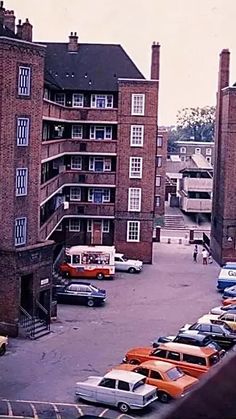 cars are parked in the parking lot next to tall brick buildings with windows and balconies