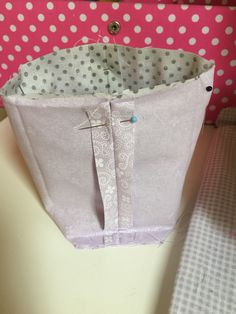 a close up of a bag on a table with polka dot wallpaper in the background