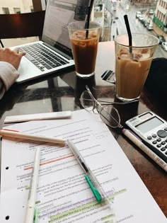 two people sitting at a table with laptops and papers