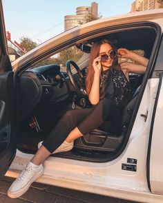 a woman sitting in the driver's seat of a car talking on her cell phone