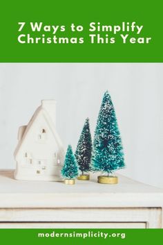 three small christmas trees sitting on top of a table next to a house and money