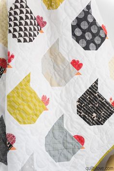 a close up of a quilt on a bed with many different colors and shapes in it