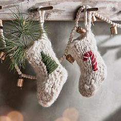 two knitted christmas stockings hanging from a wooden rack with bells and pine cones on them