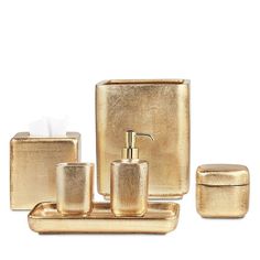 a gold bathroom set with soap dispenser, toothbrush holder and tissue dispenser