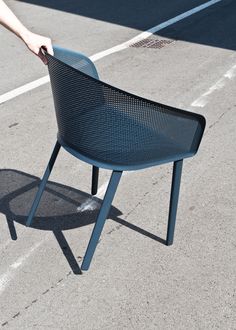 a person is reaching for a chair on the ground in an empty parking lot with no one around it