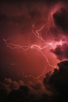 a lightning bolt is seen in the sky above some clouds and dark clouds at night