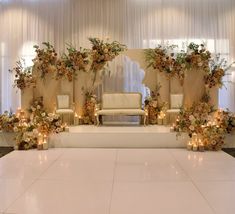 a stage set up for a wedding with candles and flowers on the floor in front of it