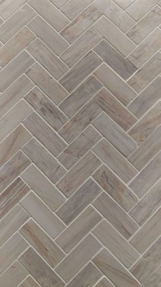 a close up view of a herringle tile pattern in white and grey tones with light brown grouting