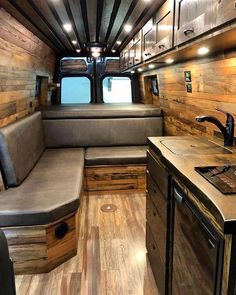 the interior of an rv with wooden walls and wood flooring, including a kitchen