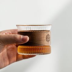 a hand holding a glass cup with some brown stuff in it