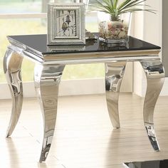 a black and silver table in front of a window next to a potted plant