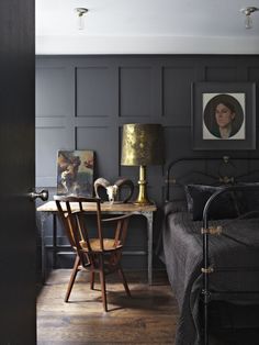 a bed room with a neatly made bed next to a night stand and a table