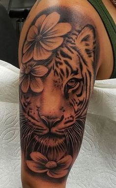 a black and white tiger with flowers on it's head is seen in this tattoo