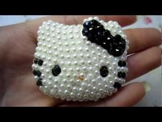 a hello kitty beaded brooch with pearls and black bows on it's head