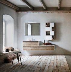 a modern bathroom with wooden flooring and white walls, along with large mirrors on the wall