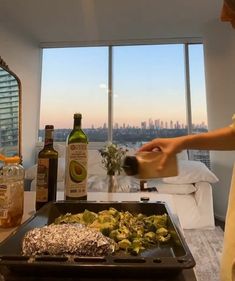 a person in an apartment cooking food on a pan with a view of the city