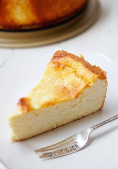 a piece of cheesecake on a white plate with a silver fork next to it