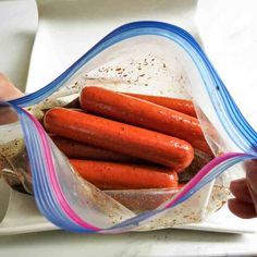 a bag filled with lots of hot dogs on top of a white counter next to a person's hand