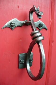 a metal door handle on the side of a red door with two bats attached to it