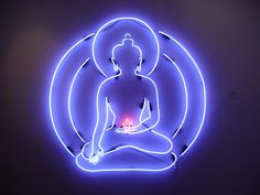 a lit up buddha sitting in the middle of a circle with a light on it