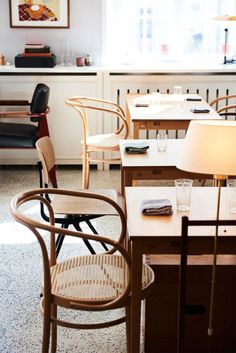 chairs and tables are arranged in a room with white walls, windows, and flooring