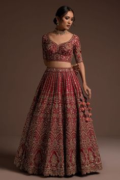 a woman in a red and gold lehenga with an intricate pattern on the skirt