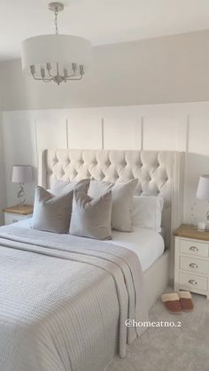 a white bed sitting in a bedroom next to a lamp and two nightstands on either side of the bed