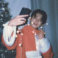 a person taking a selfie in front of a christmas tree