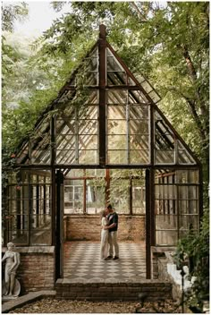 a man and woman standing in front of a glass house