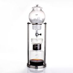 a coffee maker with a glass container on the top and two cups below it, in front of a white background