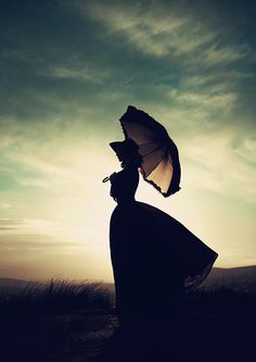 a woman with an umbrella is standing in the grass and looking up at the sky