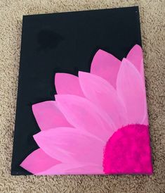 a pink and black flower painted on a piece of paper in the middle of carpet