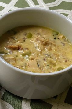 a white bowl filled with soup sitting on top of a green and white table cloth