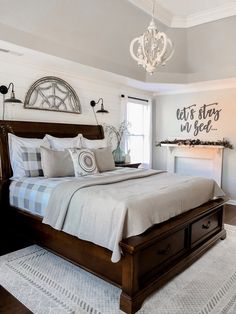 a bedroom with a bed, dresser and chandelier hanging from the ceiling in front of a window