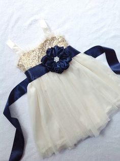 a white dress with blue flowers on it and a ribbon around the waist is shown