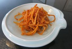 a white bowl filled with fried food on top of a black countertop next to an oven