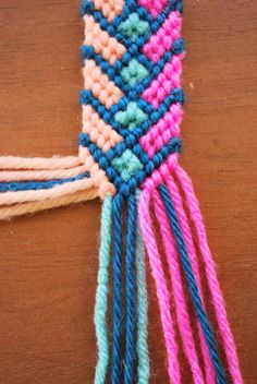 a close up of a piece of yarn on a wooden table with multicolored threads