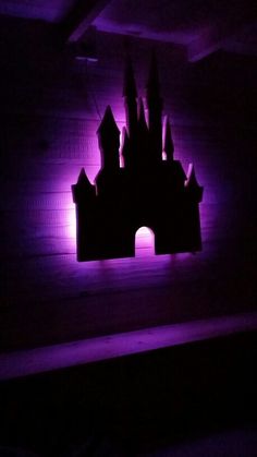 a purple light shines on a castle in the dark