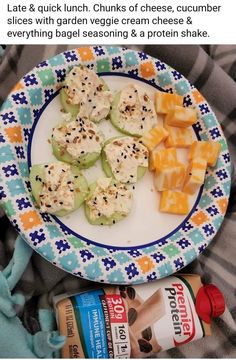 a plate with crackers, cheese and other food items on it next to a bottle of yogurt