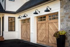 three wooden garage doors on the side of a house