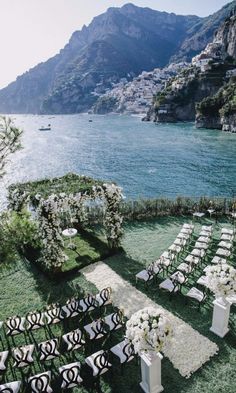 an outdoor ceremony set up with white flowers and greenery on the grass by the water