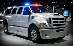 a large white truck parked on top of a cement floor next to other trucks in a showroom