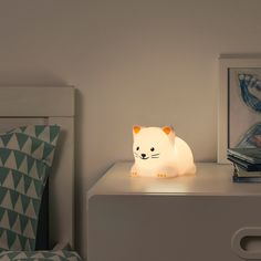 a white cat lamp sitting on top of a night stand