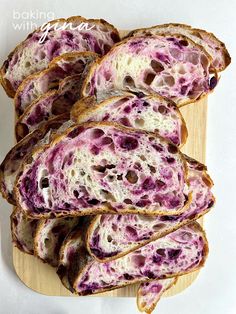 several slices of bread with purple swirled toppings on a wooden cutting board next to a white background