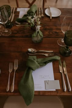 the table is set with silverware and green napkins