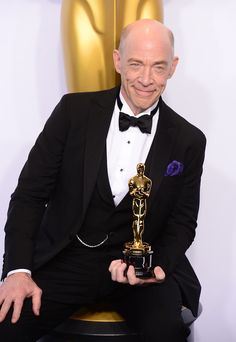 an older man in a tuxedo holding up his oscar statue