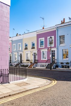 a row of colorful houses on the corner of a street in front of a pink building