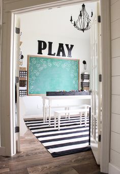 a room with a black and white striped rug on the floor next to a chalkboard